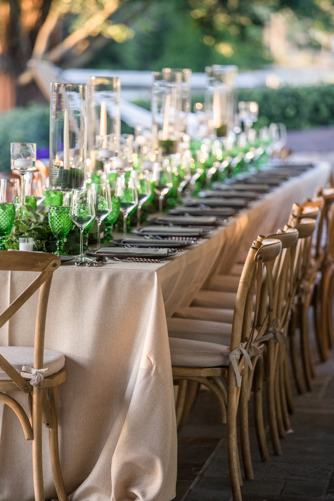 A long candlelit table outdoors at dusk
