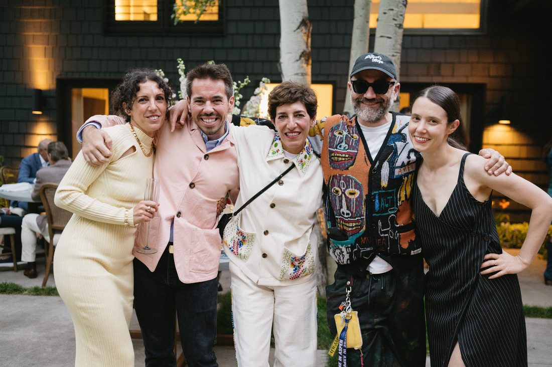 Five friends arm in arm, smiling, at an evening party in the courtyard of a home, catered by Michelle Bernstein Catering