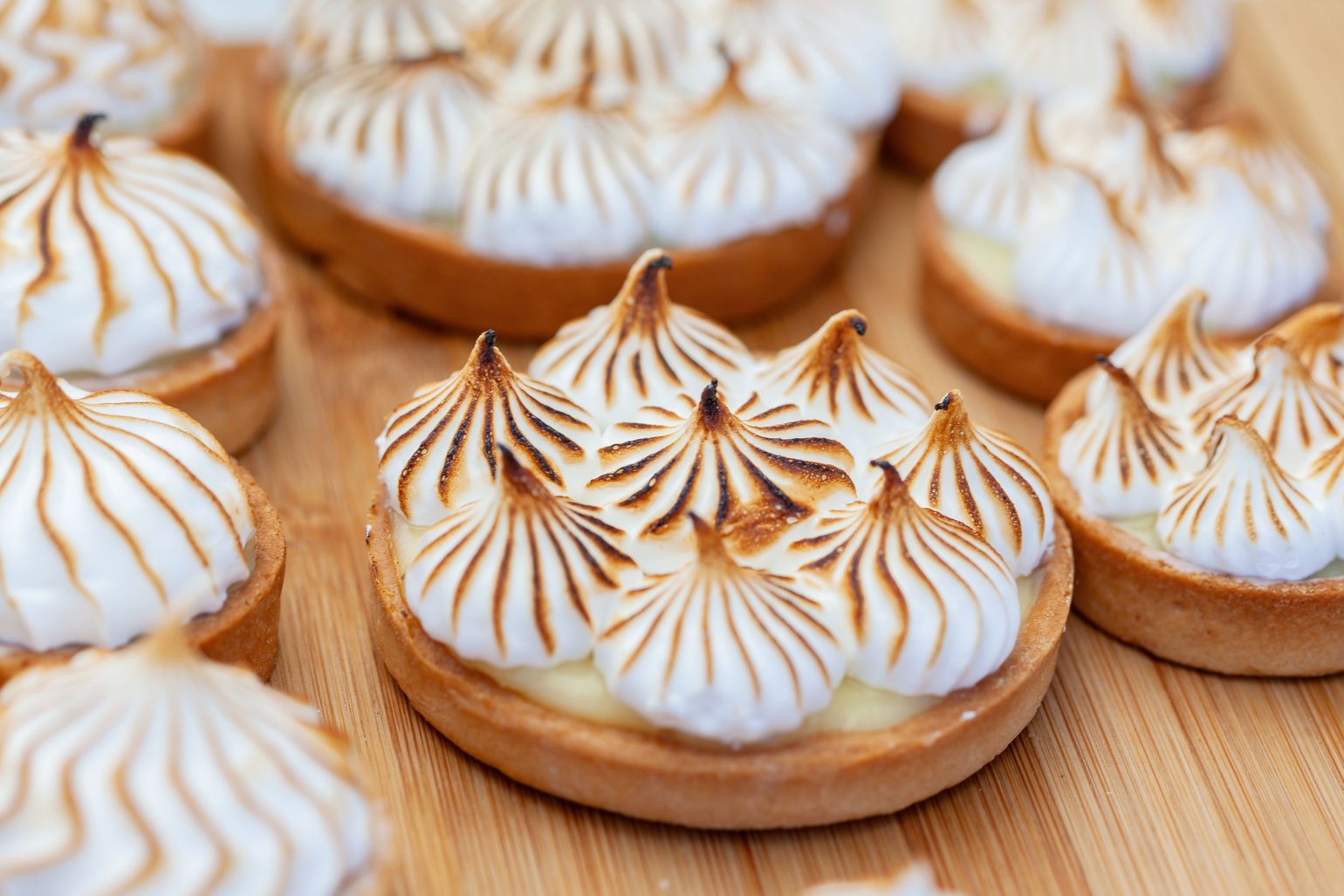 Toasted meringue tartlets with golden peaks, set close together.